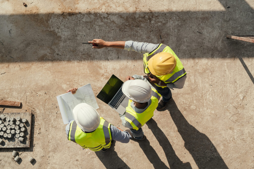 Top view, Team engineer performing inspection with tablet computer and blueprint working at construction site